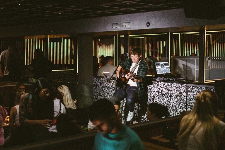 Singer playing guitar with a bar full of people